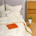 Beżowa kołdra amz basic na łóżku z poduszkami